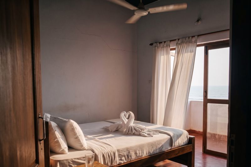 A sea-facing homestay room made up for arrival, towels folded into swans on the bed